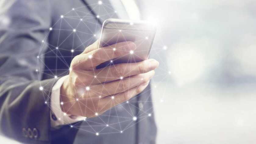 Close of of man in suit holding his cell phone with an overlaid globe made of lines and dots