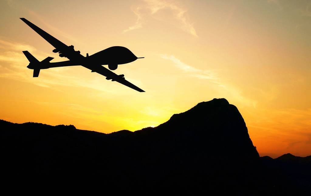 Darkened UAV flying above hills during sunset